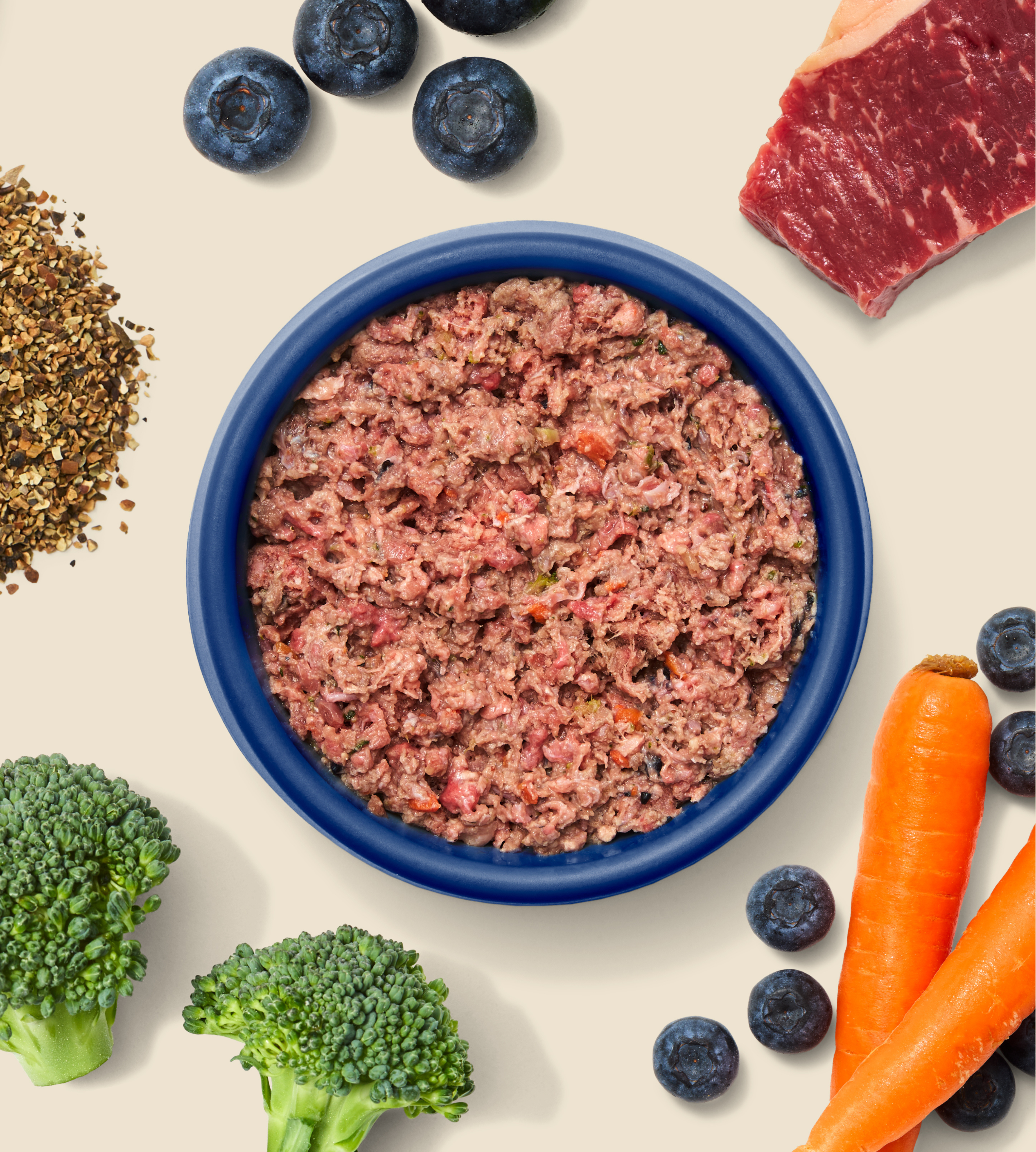 A bowl of high quality ZooperBowl hypoallergenic meat mince, surrounded by some the healthy ingredients that it contains - Broccoli, Kelp, Blueberries, Meat and Carrots